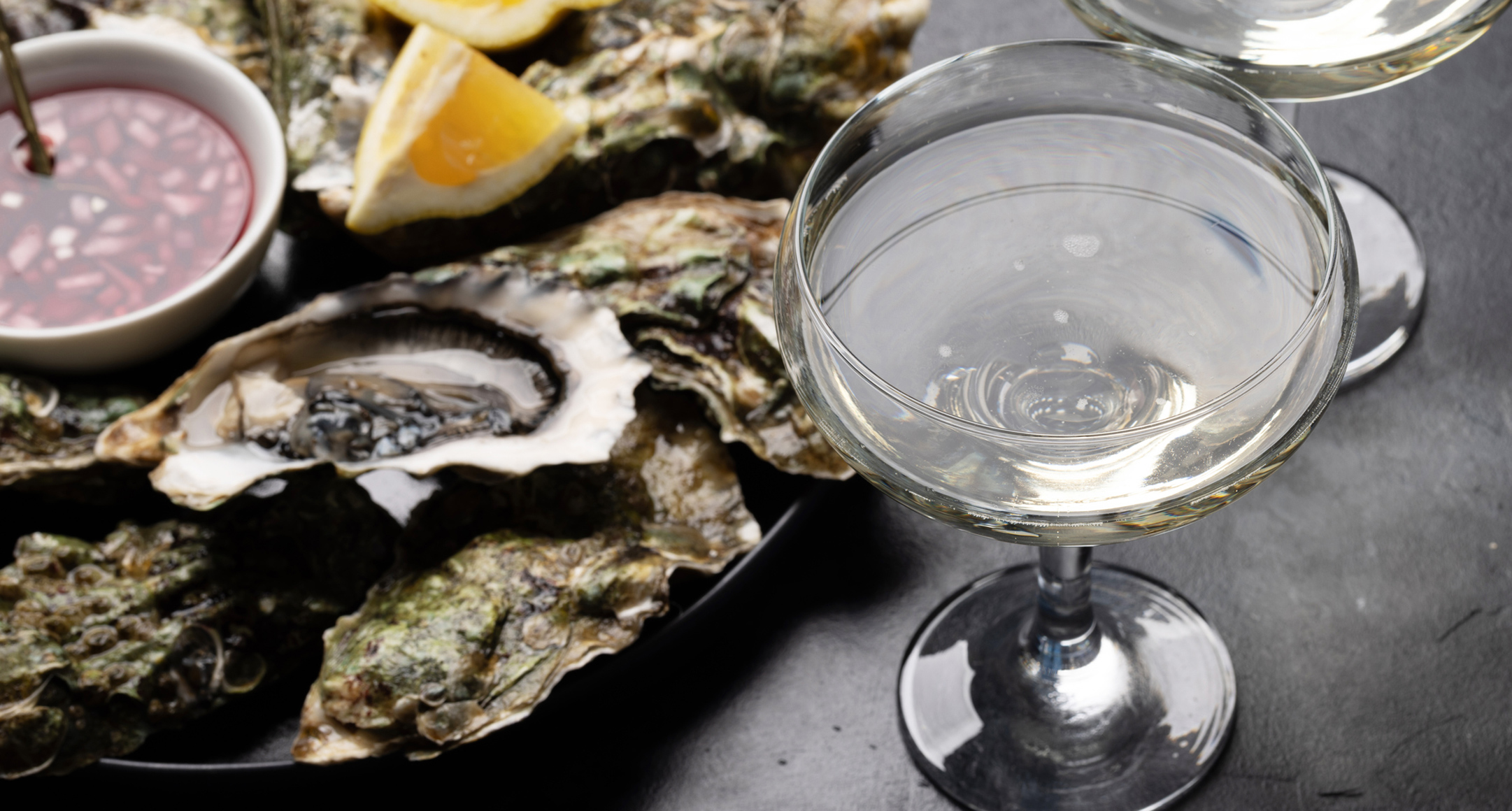 A bottle of prosecco alongside a tray of freshly shucked oysters.
