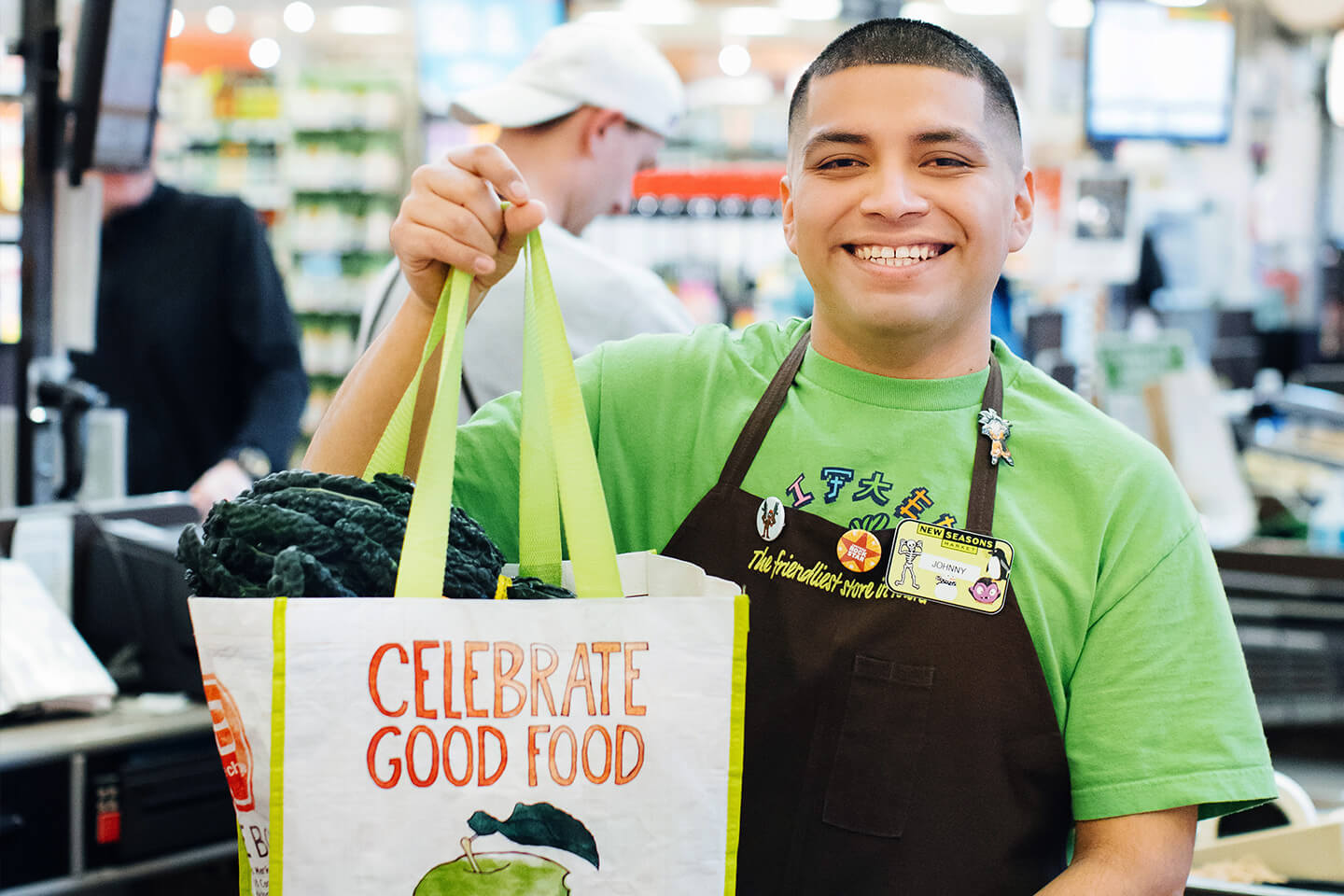 Smiling new seasons market team member holding reusable grocery bag