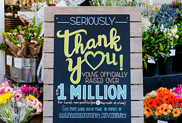 chalk sign with text in front of flowers saying thank you for 1 million in donations