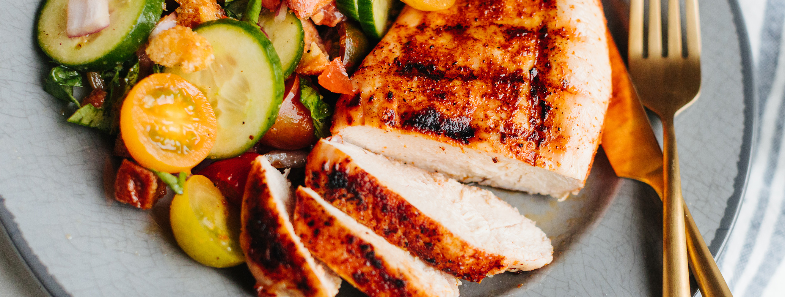 grilled chicken breast sliced on a plate with fresh vegetables