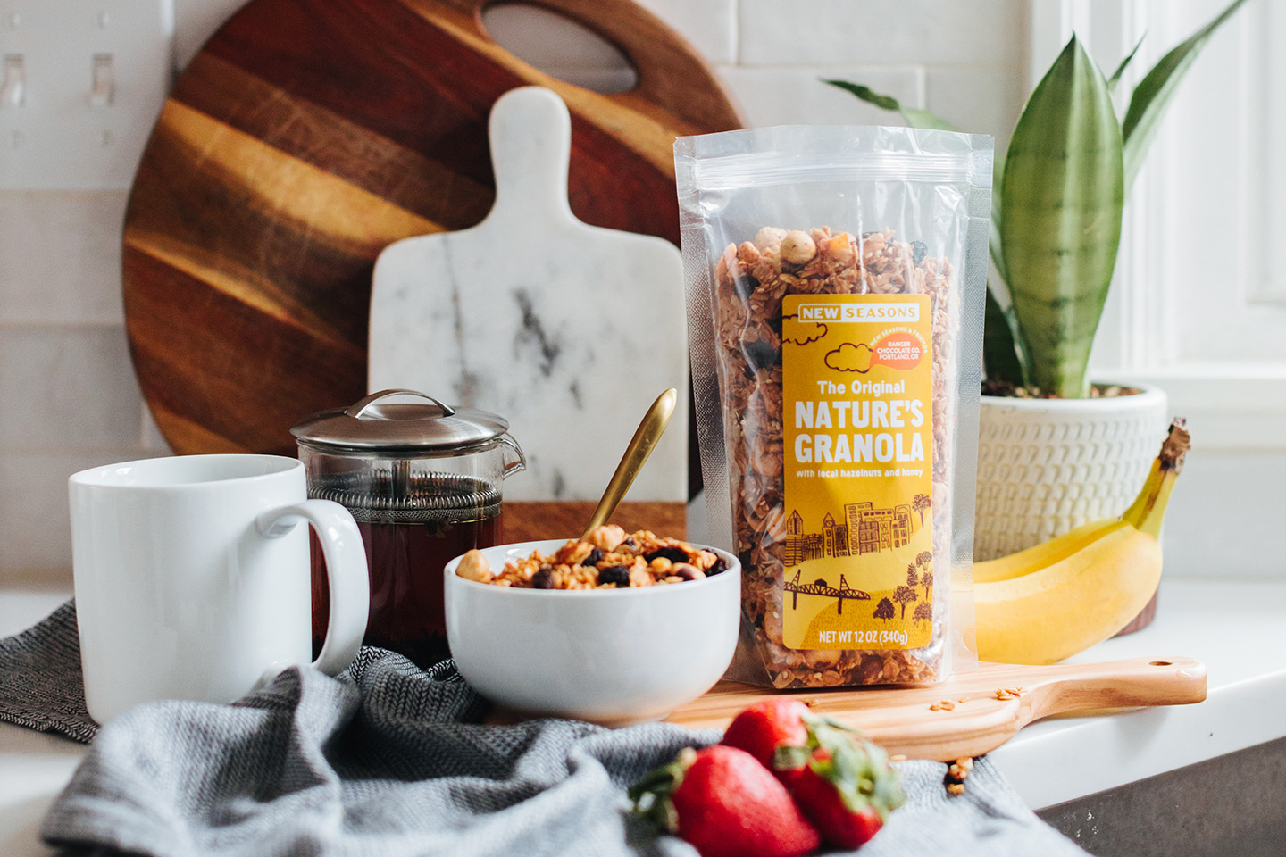 Cutting boards, a cup of coffee, and partner brand granola on a marble countertop